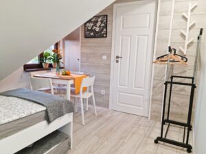 jasny pokój z łóżkiem, stolikiem i wieszakami