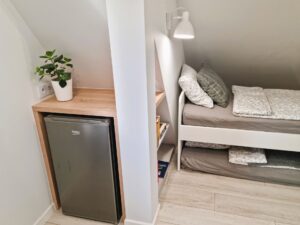 pokój z małą lodówką i łóżkiem oraz dodatkowym materacem