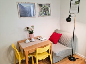 pokój z fotelem, stolikie i obrazy na ścianach