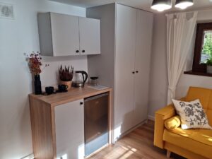 pokój z szarymi szafkami i żółtą kanapą