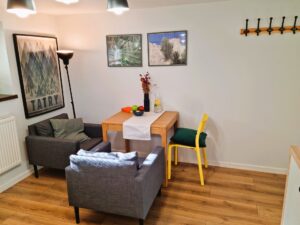 pokój ze stolikiem i dwoma fotelami, obrazy na ścianach