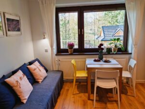 pokój z dużym oknem, stołem oraz łóżkiem