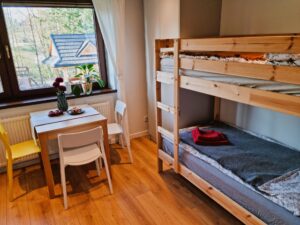 pokój z dwupoziomowym łóżkiem, szafą oraz stolikiem